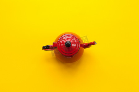 红色茶摄影照片_在纯黄色背景上的红色茶壶