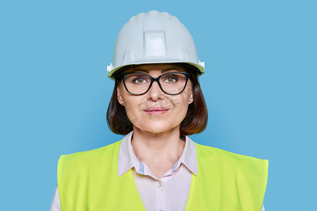 蓝色背景中戴防护安全帽和背心的女产业工人