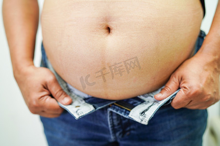 肥胖女性摄影照片_亚洲女性在办公室表现出肥胖的腹部大尺寸超重和肥胖。