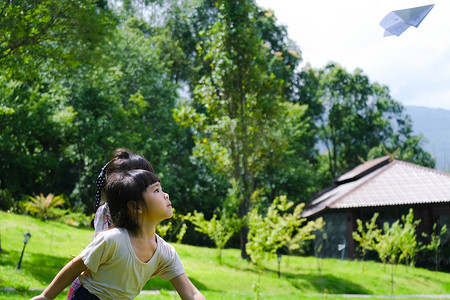 快乐的孩子们在夏日花园里玩纸飞机。