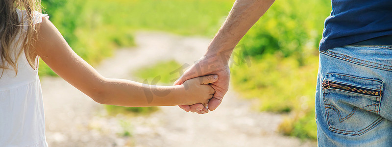 父亲和女儿手牵着手走路。