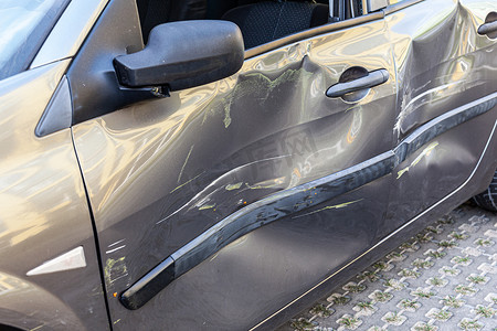 损坏的汽车，门上有划痕和凹痕，交通事故后汽车上有凹痕，