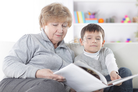 慈爱的祖母给她的孙子读一本书。照片与复制空间