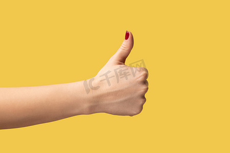 侧行摄影照片_女性手的侧视特写显示喜欢或竖起大拇指、批准、积极的反馈。
