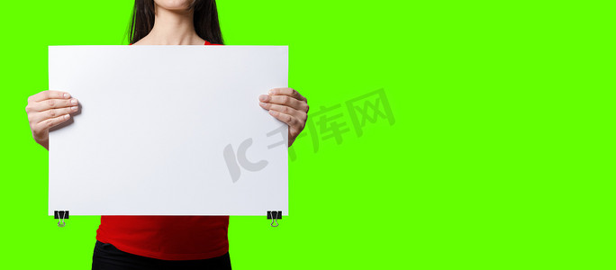 美丽的女人拿着绿色屏幕背景上的空白招牌。