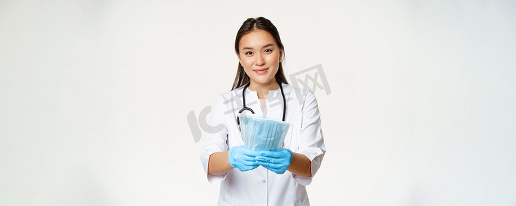 疾病预防背景摄影照片_亚洲女医生、戴橡胶手套的护士的肖像、戴无菌医用口罩、微笑、预防冠状病毒疾病的措施、白色背景