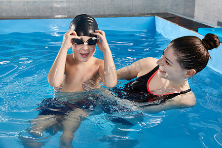 男孩和老师一起在泳池里学习游泳和潜水