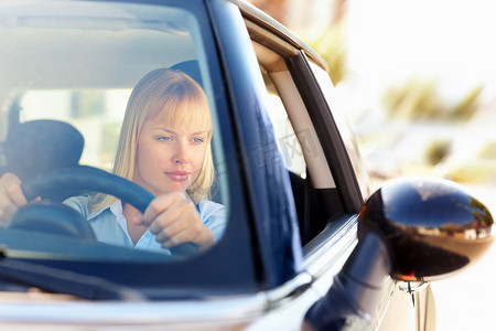 女人开车时看着后视镜。
