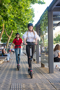 在城市环境中骑着公共租赁电动滑板车的时髦时髦的少女。