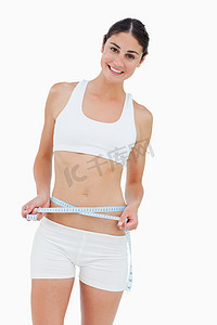 苗条女人摄影照片_测量腰部的苗条女人