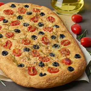 佛卡夏、披萨、意大利扁面包，配西红柿、橄榄和迷迭香，放在棕色桌子上，侧视