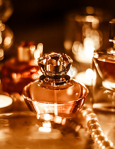 化妆品香水摄影照片_夜间魅力梳妆台上的香水瓶和复古香水、珍珠首饰和香水作为节日礼物、奢华美容品牌礼物