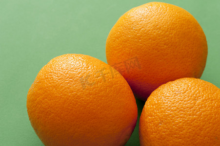 绿色背景中的三个完整的成熟橙子