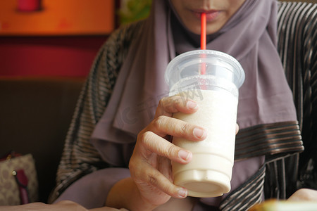 年轻女性在咖啡馆喝香蕉奶昔
