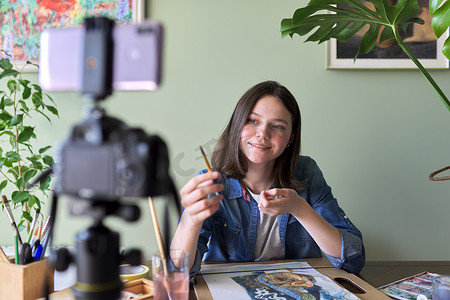 教育频道摄影照片_艺术家女孩用水彩绘画并为她的频道博客制作视频