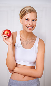 你知道他们怎么说一天一个苹果……一个美丽的年轻女子正在吃一个美味的红苹果的肖像。