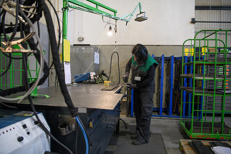 一位在现代金属生产和加工行业工作的女性焊接产品并为数控机床做好准备