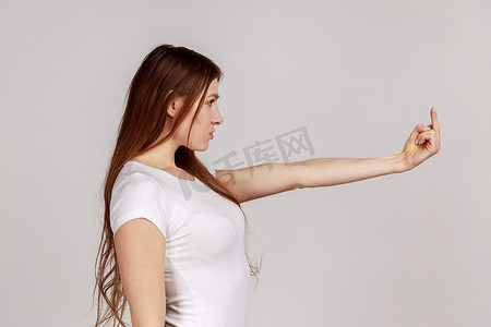 王八摄影照片_恼怒的女人的侧视图向镜头展示中指，表达抗议，打手势粗鲁的象征。