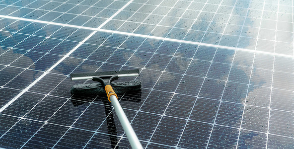 在潮湿的屋顶上用超细纤维拖把清洁太阳能电池板。