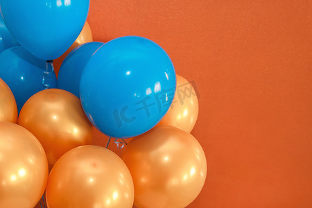 蓝色和橙色的假日气球装饰着棕色背景的内部、复制空间或文本和设计的地方