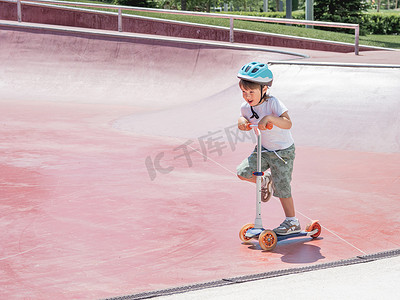 小男孩在滑板公园骑滑板车。