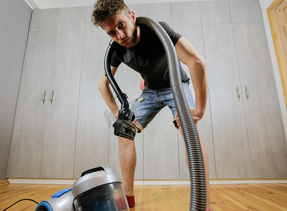 一个用吸尘器的男人厌倦了打扫房子