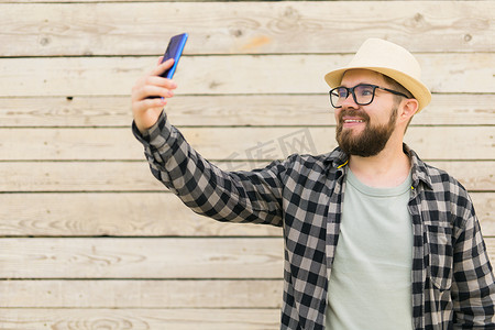 夏季城市突破木墙时，留胡子的男子用智能手机自拍 — 自拍照片和社交媒体应用程序概念
