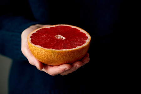 女人手握鲜半红亮柑橘类水果柚子的特写