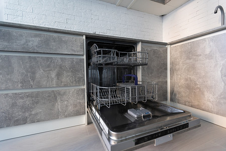 厨卫电器广告摄影照片_在配有现代家用厨柜的厨房中安装了新电器洗碗机