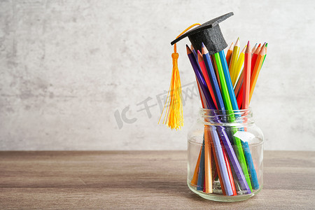 复印图标摄影照片_毕业帽上有彩色铅笔，书上有复印空间，学习大学教育理念。