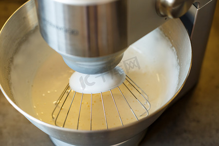 鞭子摄影照片_在食品加工机中打发甜点的奶油。