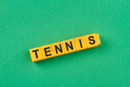 在黄色立方体上写的词网球反对绿色背景。