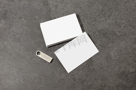 桌上空白的白色名片，带有空白的金属 U 盘。