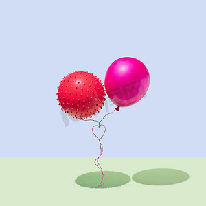 两个带有绳索的气球，形成一颗在蓝色和绿色背景上隔离的心。