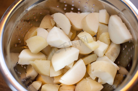 卡通沙丁鱼摄影照片_将新鲜土豆切成丁，放入金属漏勺中沥干