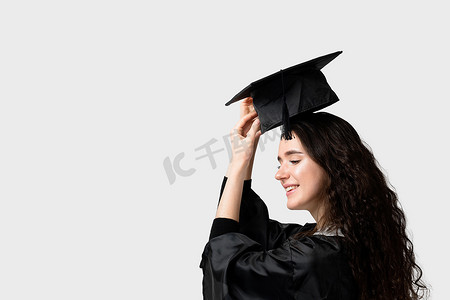 惊讶的单身女孩穿着毕业长袍和白色背景上的帽子。