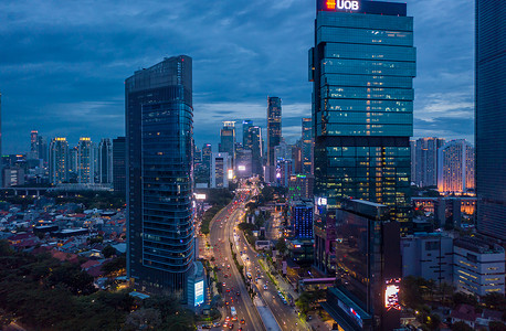 多车道高速公路穿过现代市中心的鸟瞰图，蓝色夜光中高耸的摩天大楼 2021 年印度尼西亚雅加达市中心的夜间交通