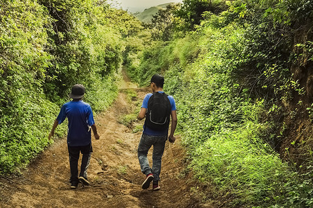 两个男人摄影照片_两个男人在穿过乡村的小路上，两个年轻人沿着有复制空间的小路行走