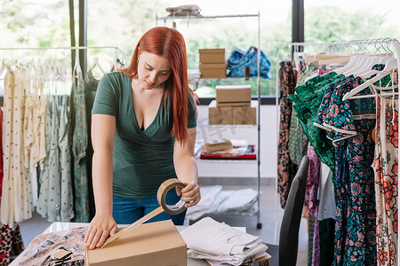 一家网上服装店的年轻女员工用胶带封住一个纸板箱，然后通过快递寄给买家。