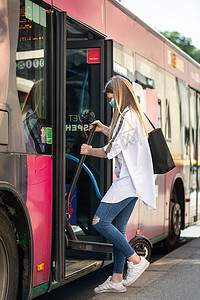 乘坐可折叠电动城市踏板车进入城市公交车的少女通勤者，在 covid-19 大流行时戴着防护面罩，防止冠状病毒传播和疾病传播