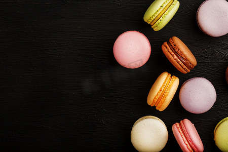 不同颜色的通心粉饼干位于黑色带纹理的背景上。