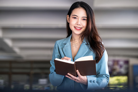 亚洲女企业家或女商人在阅读一本制定金融和投资策略的书时面带微笑。