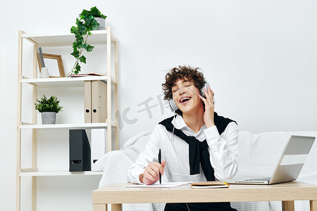 白色沙发上戴耳机的卷发男笔记本电脑 生活方式科技
