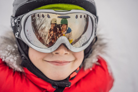 男孩滑雪护目镜中反映出妈妈和爸爸。