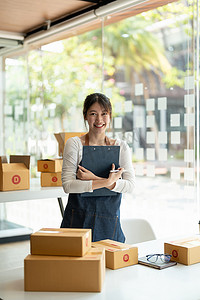 亚洲年轻女性 SME 的肖像在工作场所的家中使用盒子。初创小企业主、小企业企业家 SME 或自由职业在线和交付概念