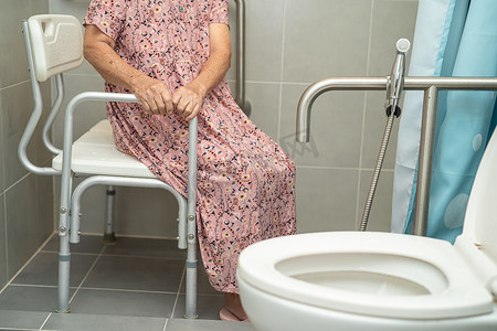 亚洲老年或老年老妇人病人在护理医院病房使用厕所浴室手柄安全，健康强大的医疗理念。