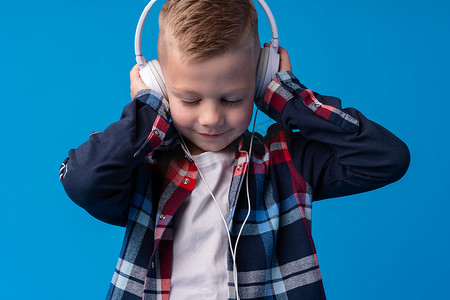 蓝色背景下戴着耳机听音乐的可爱小孩的画像