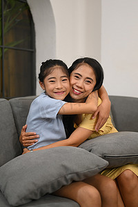 抱抱摄影照片_可爱的亚洲儿童拥抱母亲，对着镜头微笑。