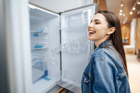 年轻漂亮的女人在大卖场选择冰箱