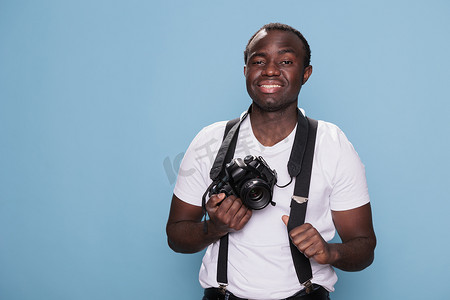 摄影爱好者摄影照片_性格开朗的非洲族摄影爱好者穿着时髦的 T 恤和吊带。